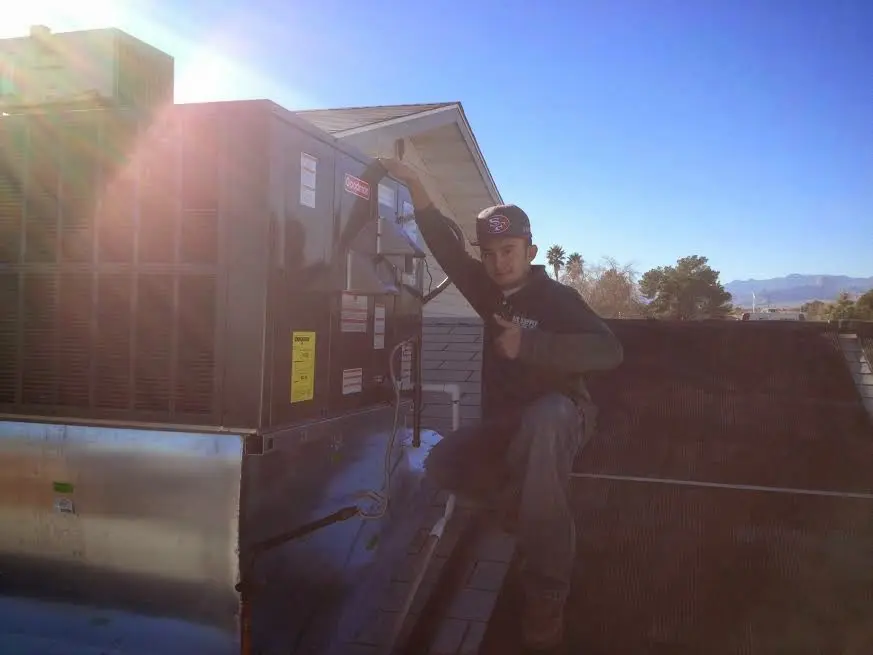 HVAC technician performing Air Duct Cleaning on a rooftop unit in Nuevo